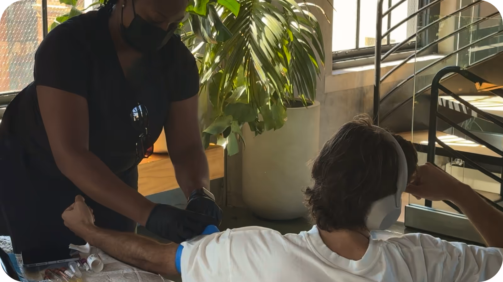 A phlebotomist drawing blood from a seated patient